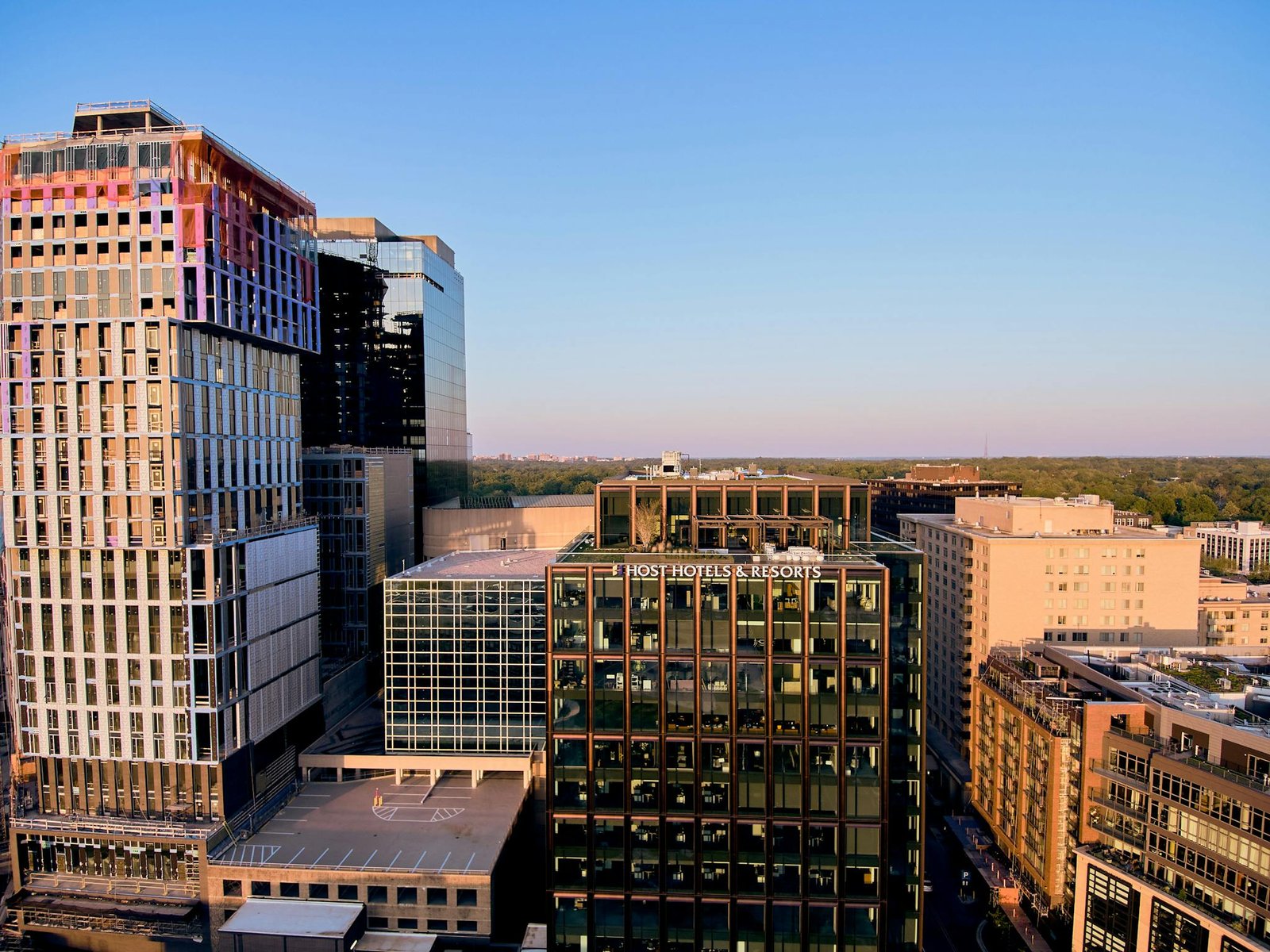 Aerial view of a modern cityscape featuring Host Hotels & Resorts during sunset, highlighting urban architecture.