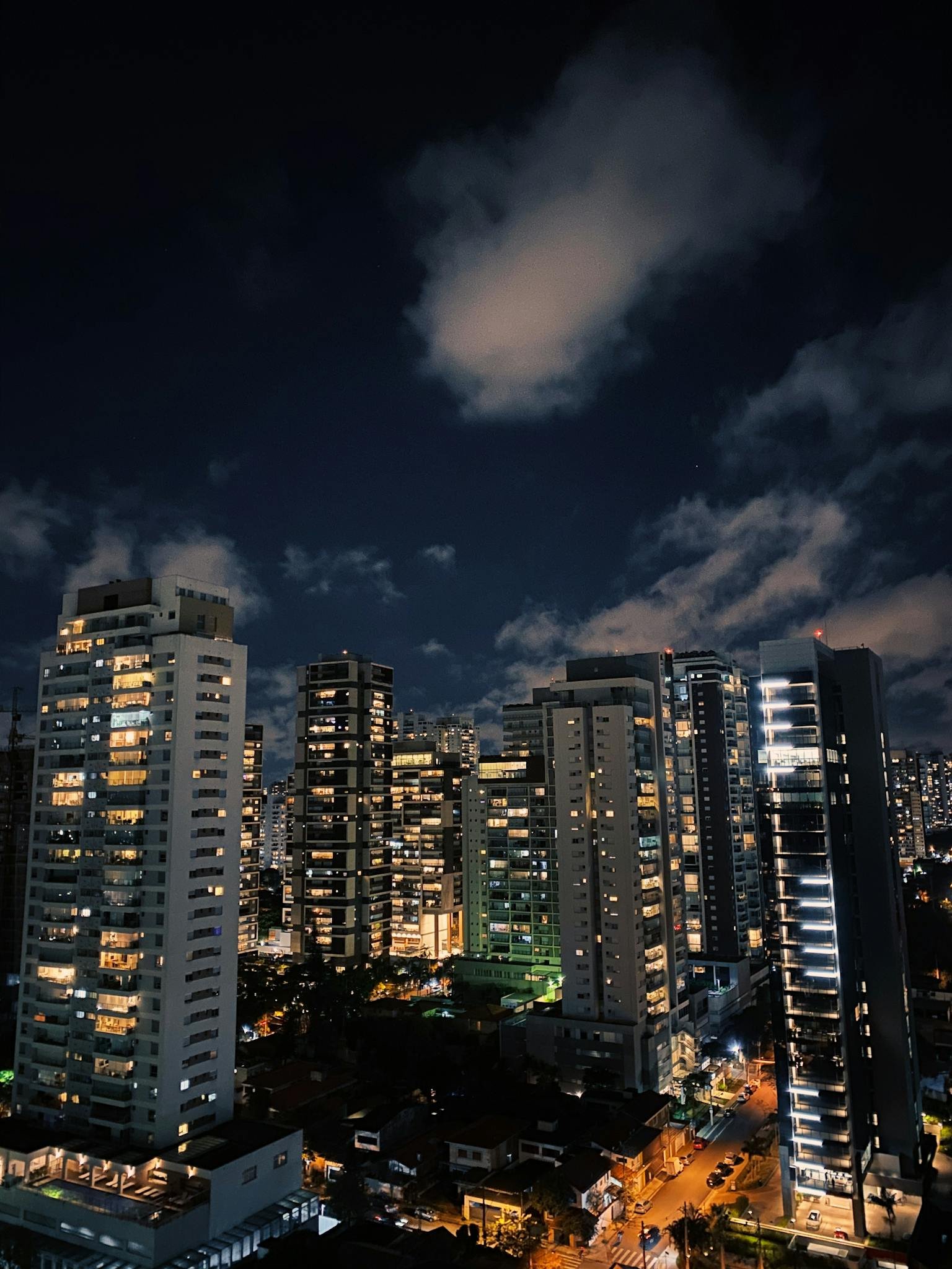 Vibrant urban skyline showcasing illuminated skyscrapers under a dramatic night sky.